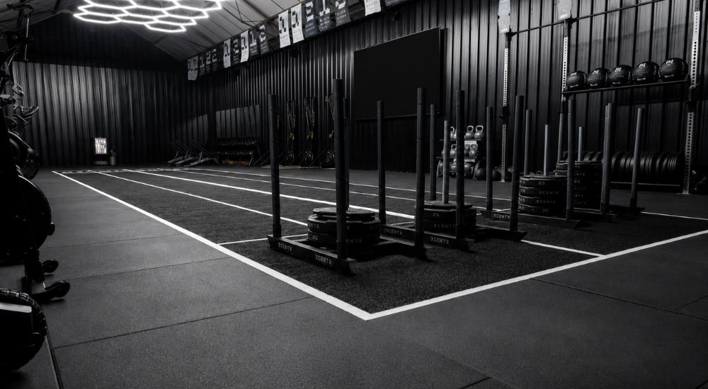 HYROX Drive performance track with tufted white lane markings and sleds in a training facility